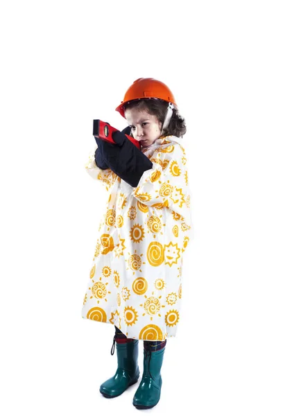 건물 레벨 holing 비옷에 귀여운 곱슬 머리 소년 빌더. 오렌지 건설 헬멧 및 건설 장갑의 포먼 흰색 배경. — 스톡 사진