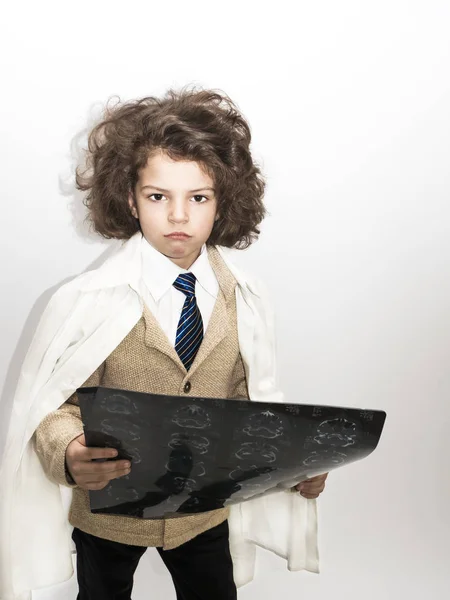 İş kıyafeti ve x-ışını gri arka plan üzerinde tutan bir laboratuar önlüğü giymiş küçük sevimli kıvırcık çocuk — Stok fotoğraf