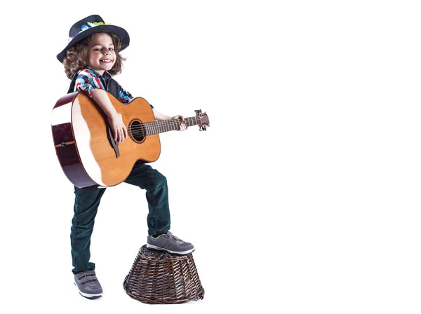 귀여운 웃는 소년 기타를 보유 하 고 카메라에서 보이는. 소년은 바구니에 그의 발을 둔다. 흰색 배경. — 스톡 사진
