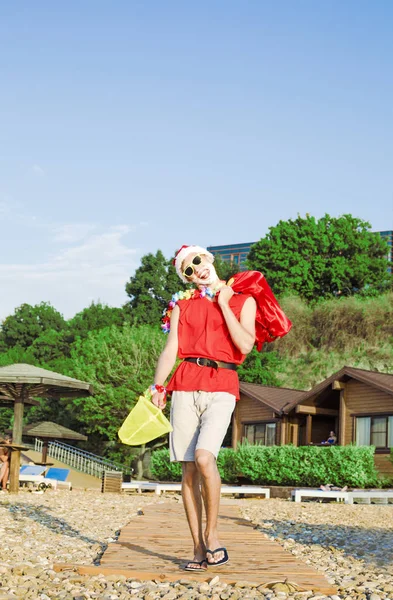 Nowy rok na plaży. Santa Claus chodzenie z workiem prezentów na plaży. Pojęcie wakacje i zabawy. — Zdjęcie stockowe