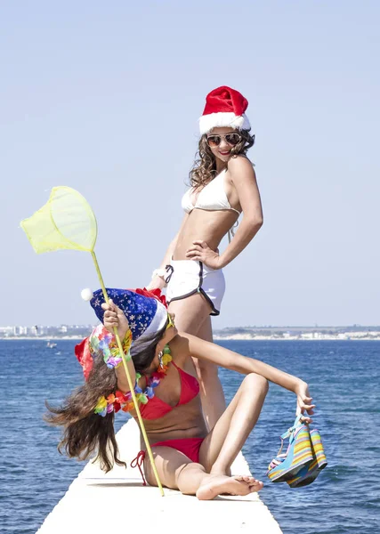 ビーチでの休暇中にサンタの帽子で 2 つのガール フレンド — ストック写真