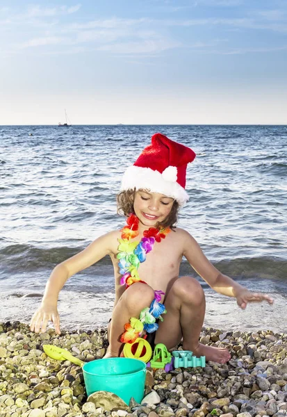 少年はビーチでおもちゃでサンタ帽子 — ストック写真