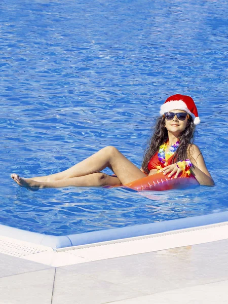 Belle jeune femme dans le chapeau du Père Noël avec beignet gonflable dans la piscine — Photo