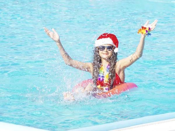 Mulher nova bonita no chapéu de Santa com donut inflável na piscina — Fotografia de Stock