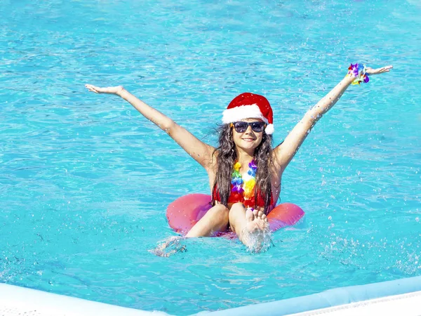 Mulher nova bonita no chapéu de Santa com donut inflável na piscina — Fotografia de Stock