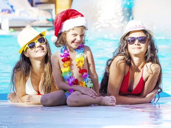 Щасливі дівчата і дитина сидять біля басейну під час Різдва — стокове фото