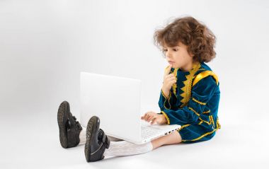 Sevimli kıvırcık saçlı çocuk laptop ile sürpriz bir yüz görünüyor..