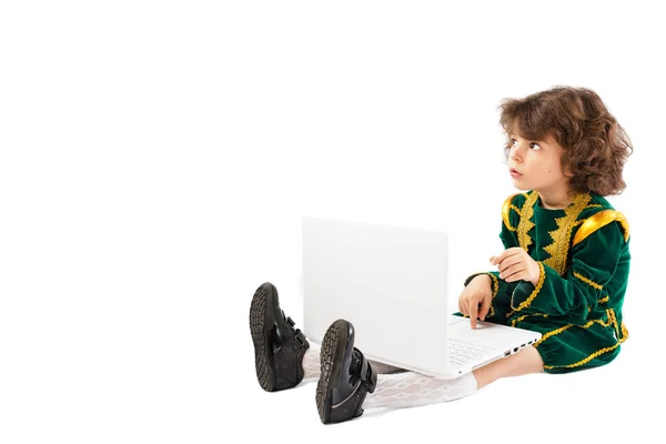 Kisfiú a padlón ül, és a laptop gépelés egy herceg jelmez. Gyermek blogolás az internet. — Stock Fotó