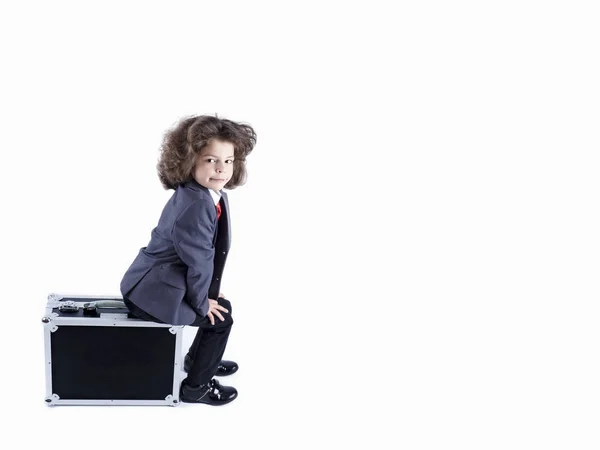 Petit garçon assis sur une valise, se préparant pour les vacances. Garçon d'affaires, enfant joyeux et actif. Voyage. Fond blanc avec espace pour le texte ou l'image . — Photo