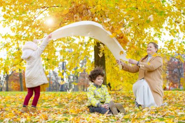 İki küçük sevimli bebek ve anneleri güzel bir sonbahar gününde eğleniyorlar. Sonbahar parkında oynayan mutlu çocuklar. Sarı sonbahar yaprakları toplayan çocuklar. Çocuklar için sonbahar aktiviteleri. Seçici odak.