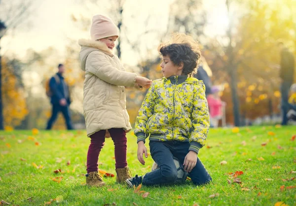 İki tatlı genç erkek ve kız kardeş güzel bir sonbahar gününde eğleniyorlar. Sonbahar parkında oynayan mutlu çocuklar. Küçük çocuklar birbirleriyle oynarlar. Çocuklar için sonbahar etkinlikleri.