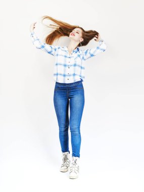 Gülümseyen bir kız saçlarını atölyedeki beyaz bir arka plandan fırlatıyor. Kırmızı dudaklar, makyaj