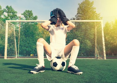 Üzgün küçük futbol kalecisi. Beyazlar içinde, elleri kafasında, spor kıyafetleri içinde hayal kırıklığına uğramış bir çocuk. Gençler futbol takımı gol kaybediyor.