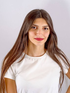 Genç bir kızın portresi. Uzun siyah saçlar, gri arka planda güzel bir yüz..