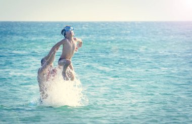 Baba ve oğul denizin içinde oynuyorlar. Yaz tatili kavramı.