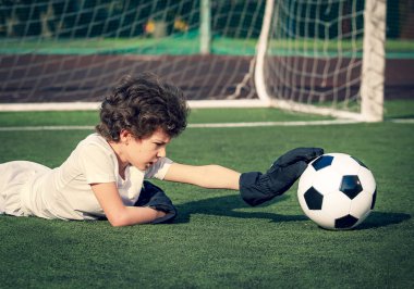Genç futbol kalecisi kurtarmayı deniyor. Eldivenli küçük bir kaleci. Çocuklar, futbol şampiyonu. Stadyumda futbol takımının erkek kalecisi. Spor konsepti.