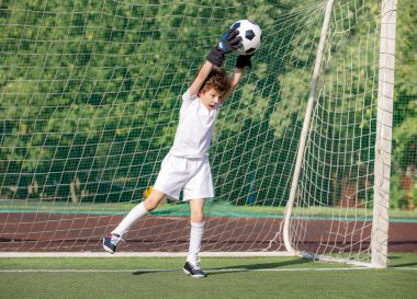 Küçük çocuklar için yaz futbol turnuvası. Futbol kulübü. Oyunun heyecanı ve neşesi. Genç kaleci. Stadyumda futbol takımının erkek kalecisi. Spor konsepti. seçici odak
