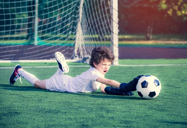 Young soccer goalie attempting to make a save. little soccer goalkeeper with gloves. Kids - soccer champion. Boy goalkeeper in football sportswear on stadium with ball. Sport concept.