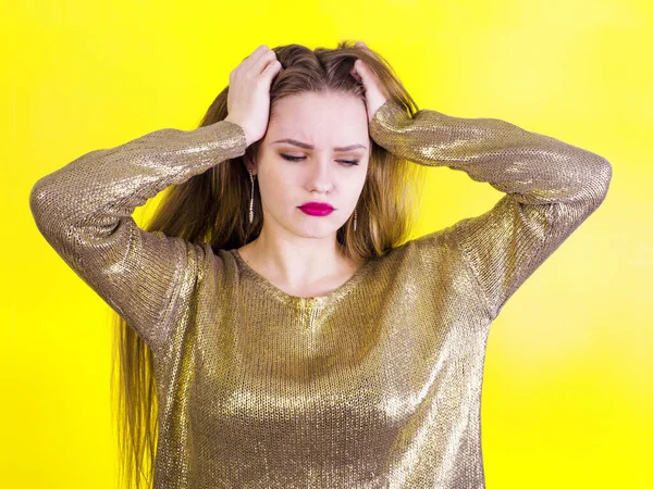 Frusztrált fiatal és gyönyörű nő úgy néz ki, ideges, depressziós, és tartja a fejét kezét a sárga háttér — Stock Fotó