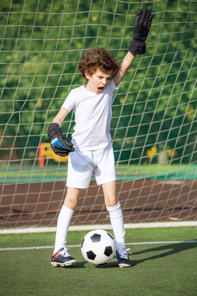 Summer soccer tournament for young kids. football club. emotions and joy of the game. Young goalie. Kids - soccer champion. Boy goalkeeper in football sportswear on stadium with ball. Sport concept.