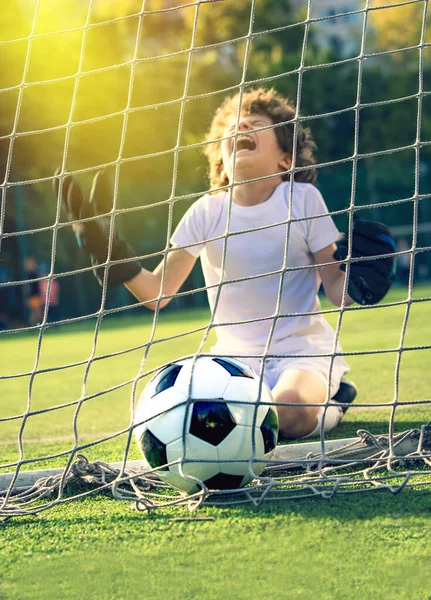 Soccer ball in goal on green grass. Disappointed football team goalkeeper following goals. Goalkeeper emotionally reacts after missed goal during game. Defeat Concept. selective focus