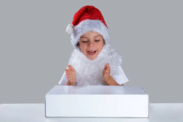 Little Santa Claus Sitting White Table Happily Looks White Box — ストック写真