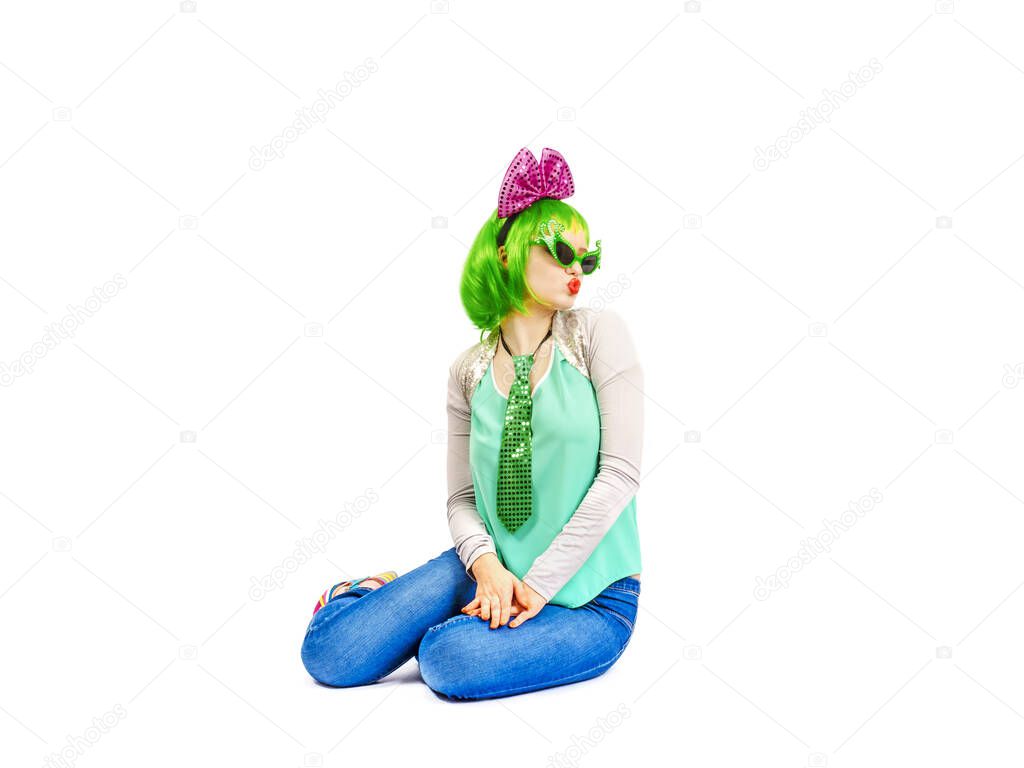 Beautiful young woman in an outrageous outfit spending time in the studio. Attractive Caucasian female model in fashion accessories and green wig, playfully posing