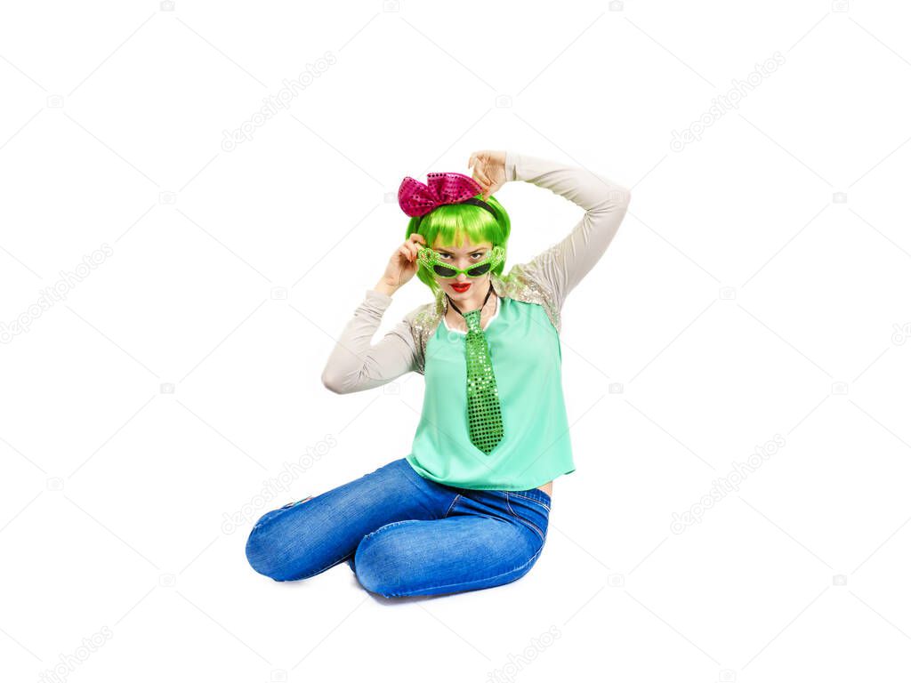 Beautiful young woman in an outrageous outfit spending time in the studio. Attractive Caucasian female model in fashion accessories and green wig, playfully posing