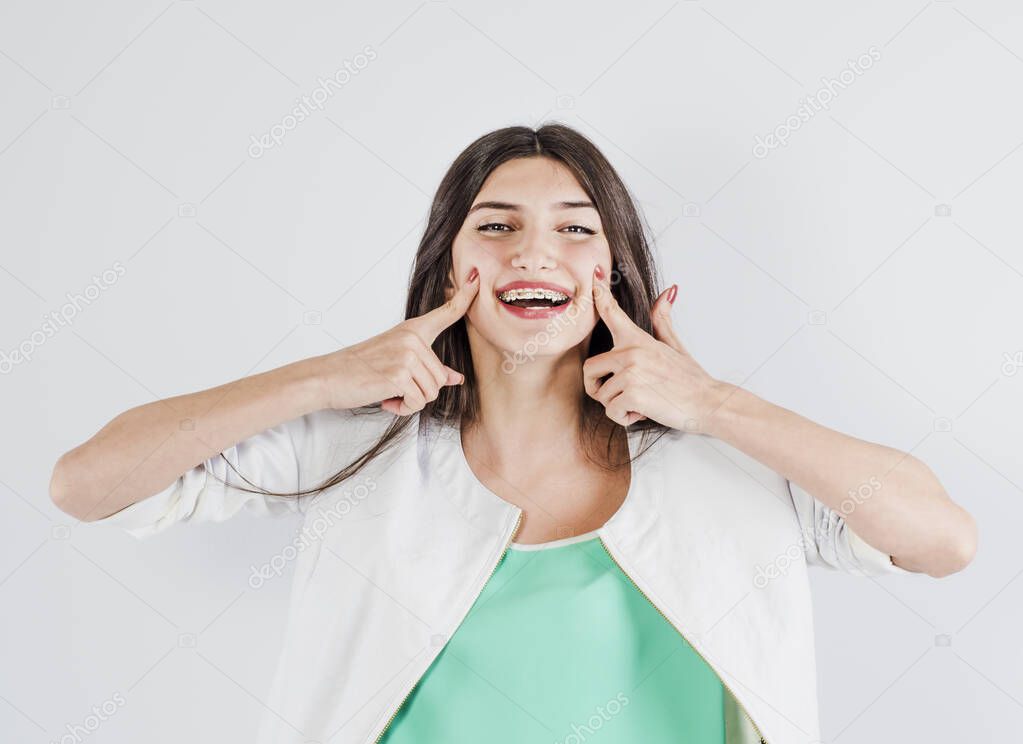 Orthodontist dentistry treatment concept. Happy smiling woman pointing at her dental braces on teeth