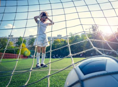 Genç erkek ya da çocuk spor yapmak ve spor yapmak için futbol oynuyor. Gol ağlarının arkasından bak. seçici odak