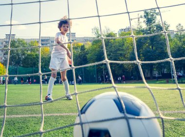 Genç erkek ya da çocuk spor yapmak ve spor yapmak için futbol oynuyor. Gol ağlarının arkasından bak. seçici odak