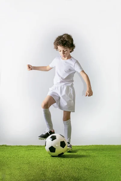 少年足球运动员在灰暗的背景下踢一个孤立的球 — 图库照片