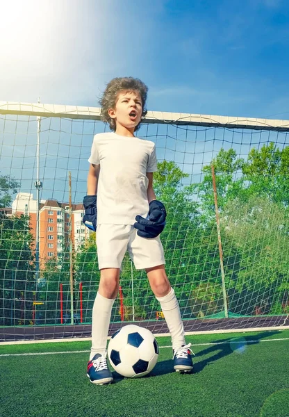 Summer soccer tournament for young kids. football club. emotions and joy of the game. Young goalie. Kids - soccer champion. Boy goalkeeper in football sportswear on stadium with ball. Sport concept.