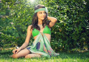 Deniz kıyısında renkli mayolu, makyajlı, güzel esmer ergen modelin portresi. Çimlerin üzerinde mayo giymiş genç ve güzel bir kız.