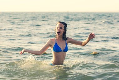 Koyu renk saçlı, ıslak bir kadının portresi. Bir yaz akşamı, batan güneşin ışığında mayo giymiş genç bir kadın..