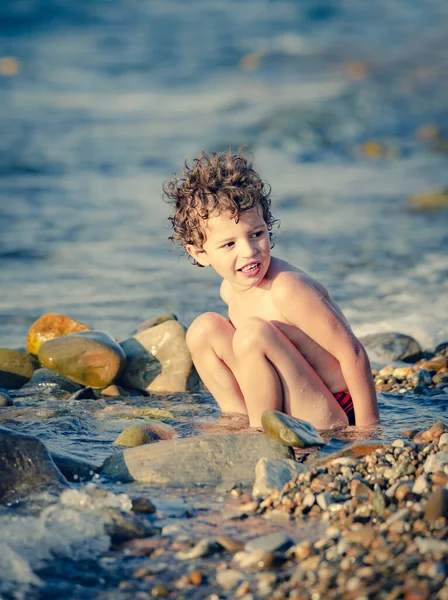 Trillende Kleine Jongen Zit Een Kiezelstrand Buurt Van Het Water — Stockfoto