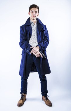 Gizemli, gizli görevdeki genç bir gangster silah tutuyor ve arka planda izole edilmiş koyu renk bir ceket giyiyor.