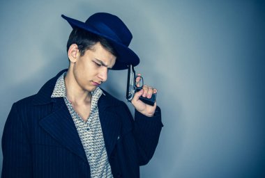 Şapkalı genç suikastçı silahını tutuyor ve dikkatlice aşağıya bakıyor.