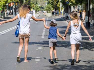 Bir çocuk onun ablası ile bir sıcak yaz gününde sokakta yürüyor. Sevgi ve destek için küçük kız kardeşlerin ifadesi. Anne, kızı ve oğlu aşk.