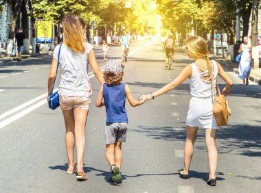 Bir çocuk onun ablası ile bir sıcak yaz gününde sokakta yürüyor. Sevgi ve destek için küçük kız kardeşlerin ifadesi. Anne, kızı ve oğlu aşk.
