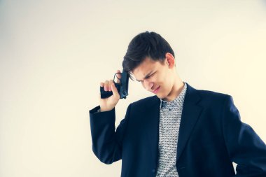 İş ceketli ve silahlı genç bir adam yoğun bir şekilde bir şeyi yansıtıyor. Düşünceli casus. Boşluğu kopyala