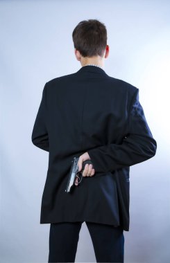 Sırtına silah dayamış bir adam. Silahlı adam silahını arkasında tutuyordu. Suç kavramı. Suç kavramı. Arka plan