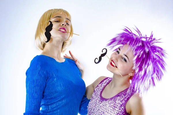 Atractivas mujeres jóvenes juguetonas listas para fiestas de carnaval. Lifestyle y el concepto de amistad: un grupo de dos amigas. Aislado en gris —  Fotos de Stock