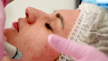 Güzellik salonunda kozmetik tedavi gören genç bir bayanın portresi, yüz temizleme için profesyonel bir alet.