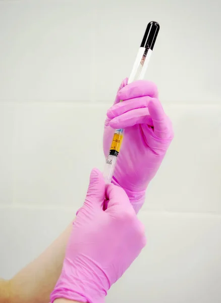 Elinde plazma olan bir şırınga. Gri arka planda yakın plan lastik eldiven. Yardımcı terapi