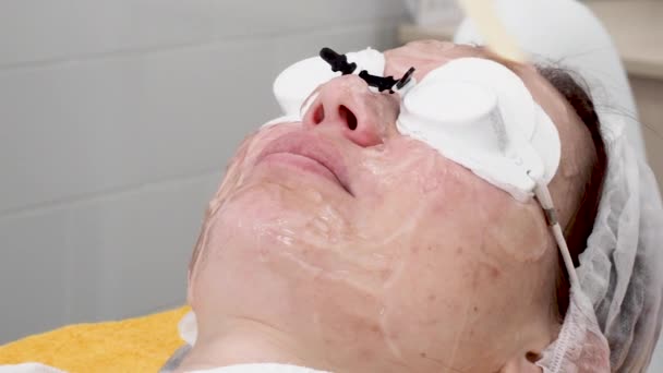 治療前の女性の顔にジェルを塗る医師 — ストック動画