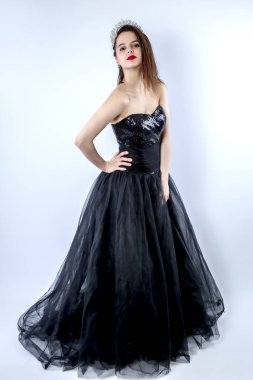 Gri arka planda zarif siyah elbisesi olan baştan çıkarıcı beyaz bir kadının portresi. İzole edilmiş