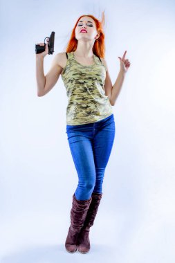 Arka planda silahı olan genç bir kadın gangster. Şapkalı, silahlı güzel bir kızıl kız portresi..