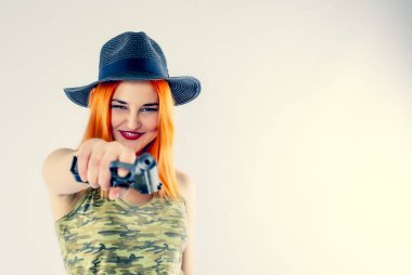 Arka planda silahı olan genç bir kadın gangster. Silahlı, şapkalı güzel bir kızıl saçlı kızın portresi. Uzayı kopyala Kırmızı canavar.
