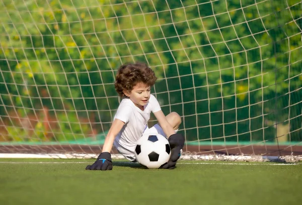 Summer soccer tournament for young kids. football club. emotions and joy of the game. Young goalie. Kids - soccer champion. Boy goalkeeper in football sportswear on stadium with ball. Sport concept.